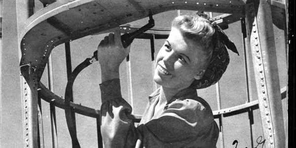 Black and White photo of woman working on world war 2 airplane. 