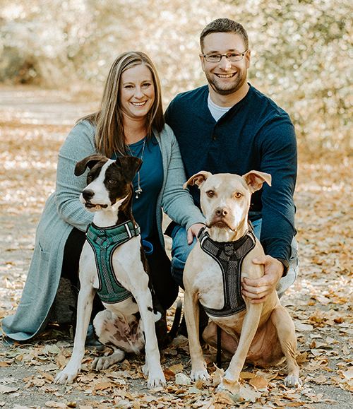 wife and husband posed with their two dogs.