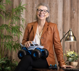 Woman sits on desk with toy truck.