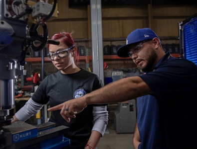 A woman being instructed on how to use a piece of machinery.  