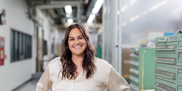 Woman in production facility facing camera and smiling. 