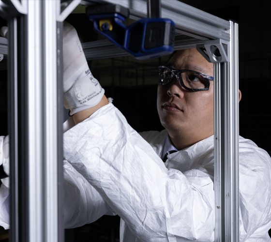 photo of man working on equipment with white oversuit and gloves