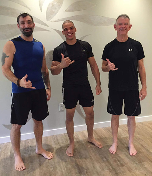 three men in workout clothes smiling at camera