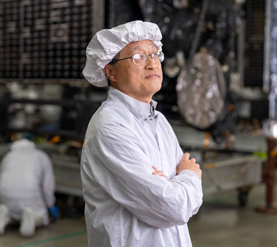 Image of person in clean room lab clothes smiling. 