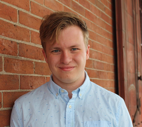 Photo of young man smiling in button down shirt.