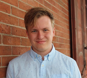 Photo of young man smiling in button down shirt.