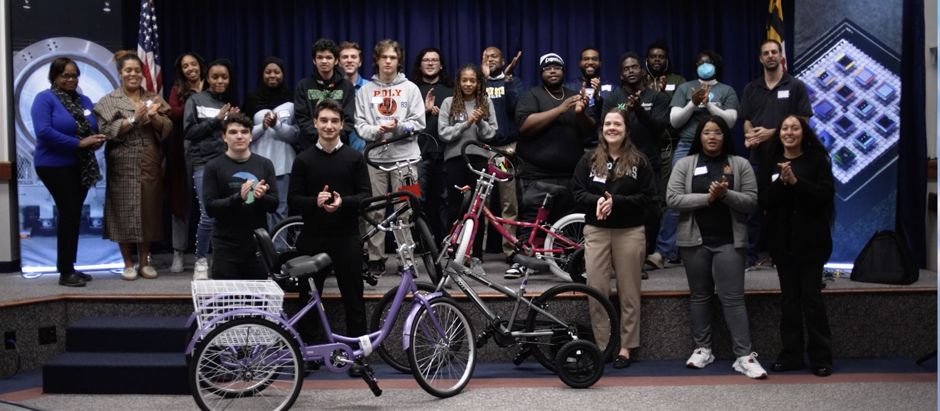 Large group of people standing on a stage around bikes.  