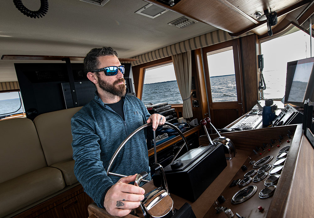 Ryan Silbaugh, manager of maritime test, captains the Sperry Star, a 70-foot command and control vessel man captains boat in cockpit