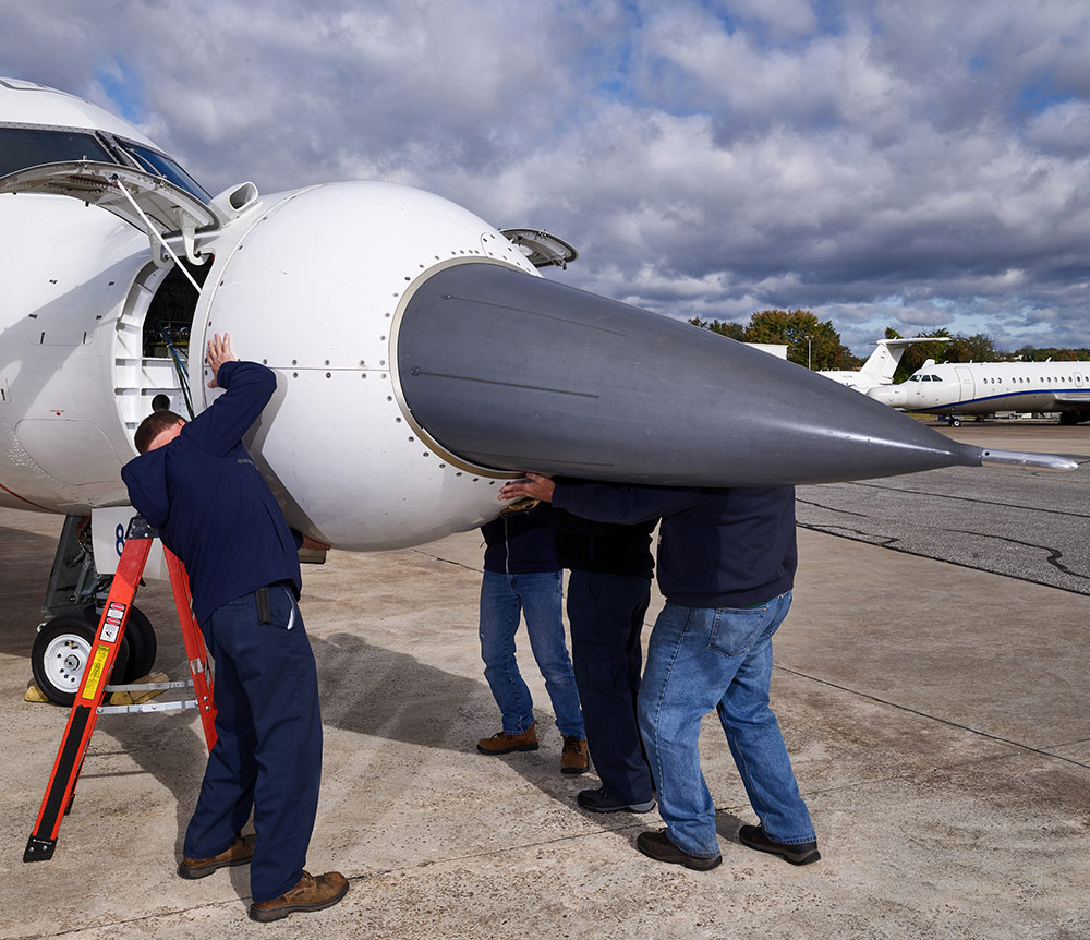 SABR - Technicians service a radar on a CRJ-700 test plane. radar in nose of jet being replaced by technicians