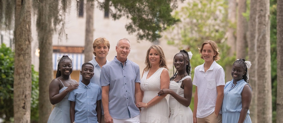 Family pose for portrait outside, two parents and six kids. 