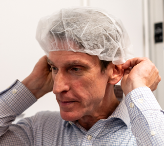 Image of man putting on hair covering for clean room.
