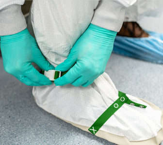 Image of man fastening clean room covering around feet.