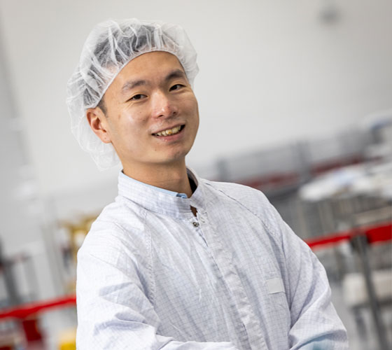 Image of person in clean room lab clothes smiling. 