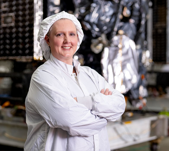 Image of woman in clean room lab clothes smiling. 