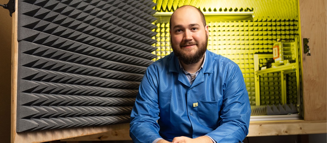 Man in blue work jacket sits in yellow testing environment.