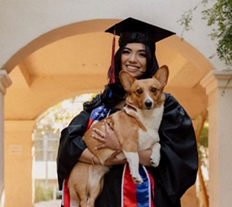 woman in graduation regalia holding dog