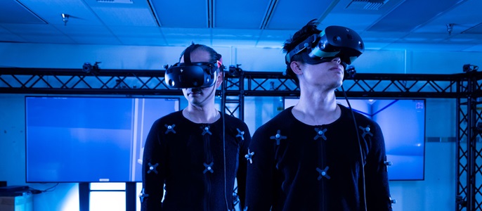 Two men wearing HIVE body suits in a dark room