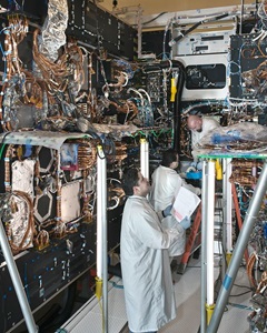 two engineers in clean suits working on spacecraft