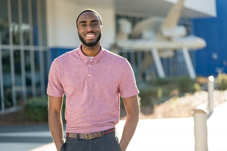 black male wearing pink shirt smiling