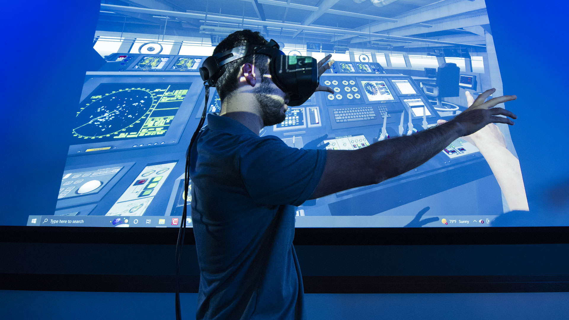 Man with virtual reality googles reaching in front of him in darkened room.