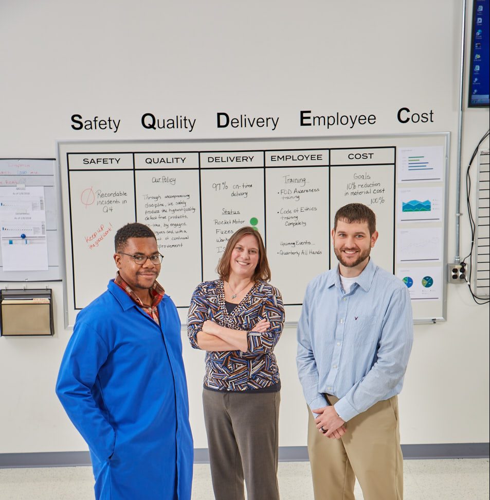 Two males and one female standing in front of white board