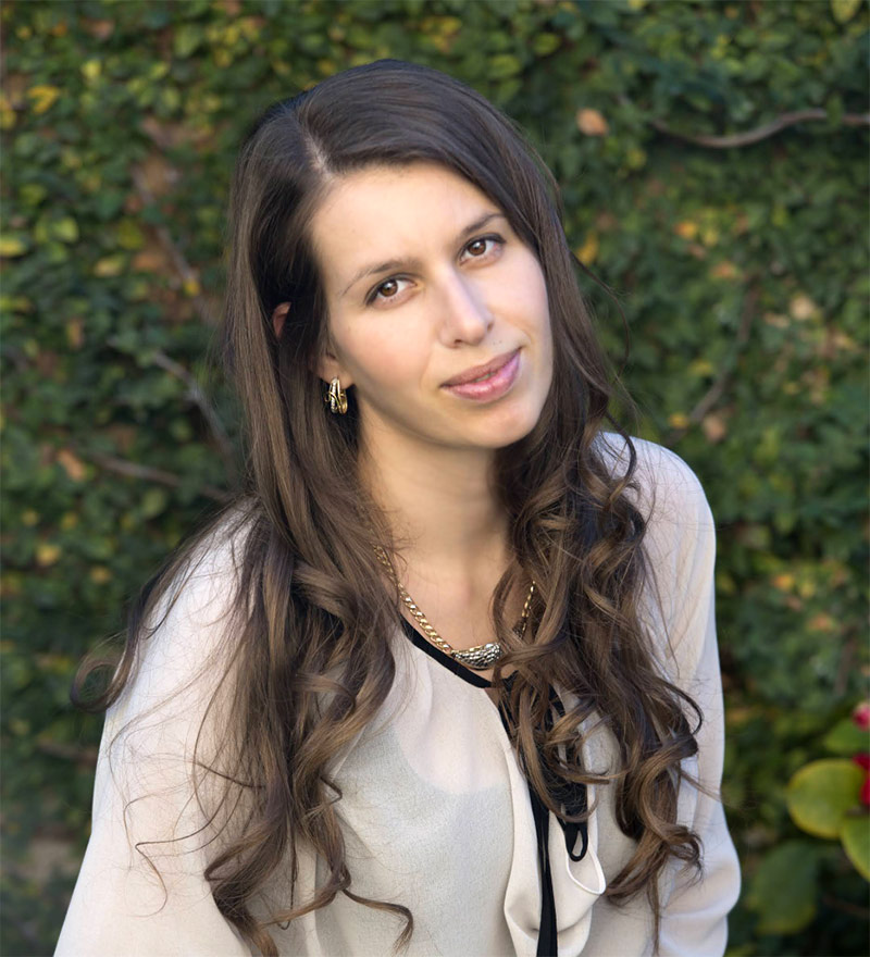 woman with long brown hair in front of green ivy wall