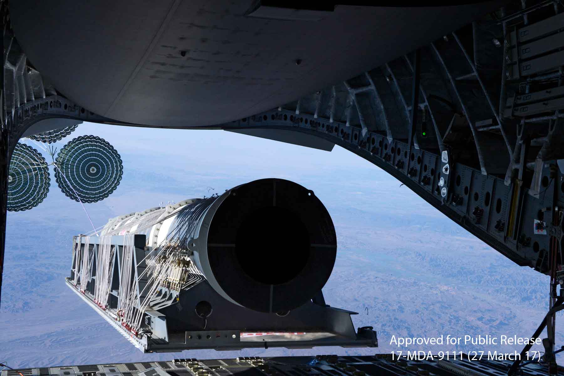 An airdrop load is extracted with parachutes from a C-17 cargo hold