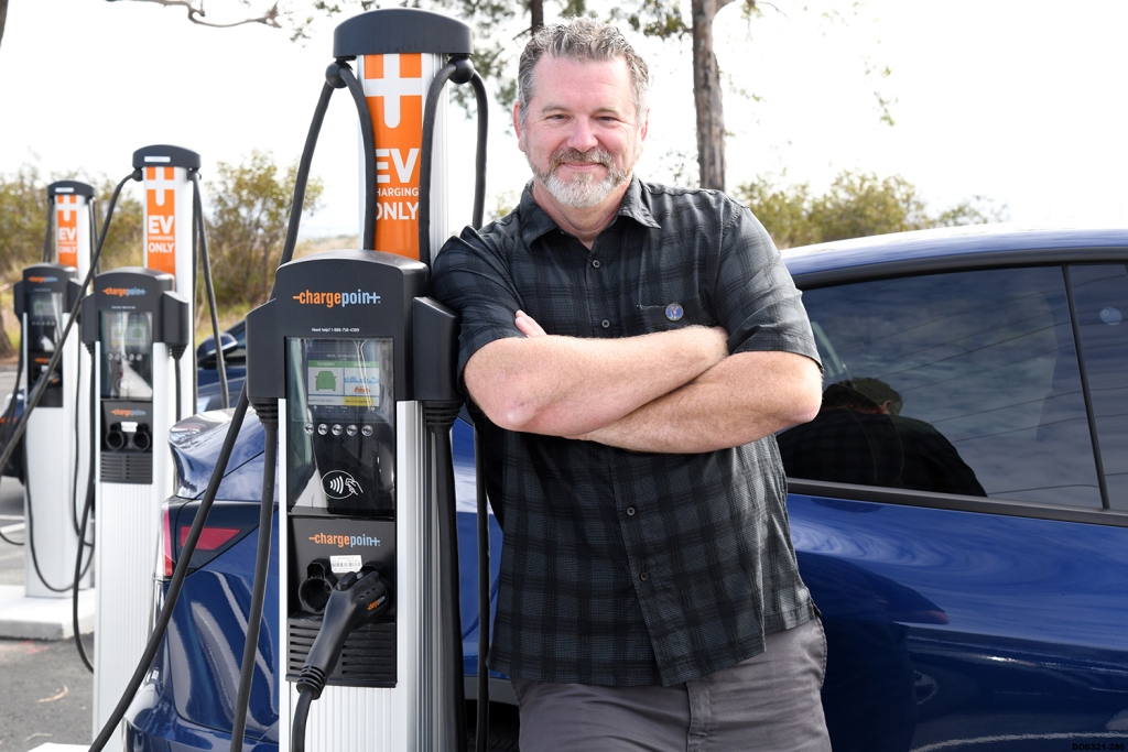 Man standing in front of electric charger with his arms crossed
