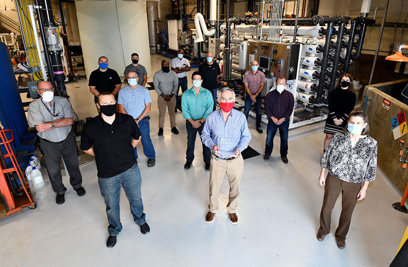 group of people standing in front of water recycling equipment