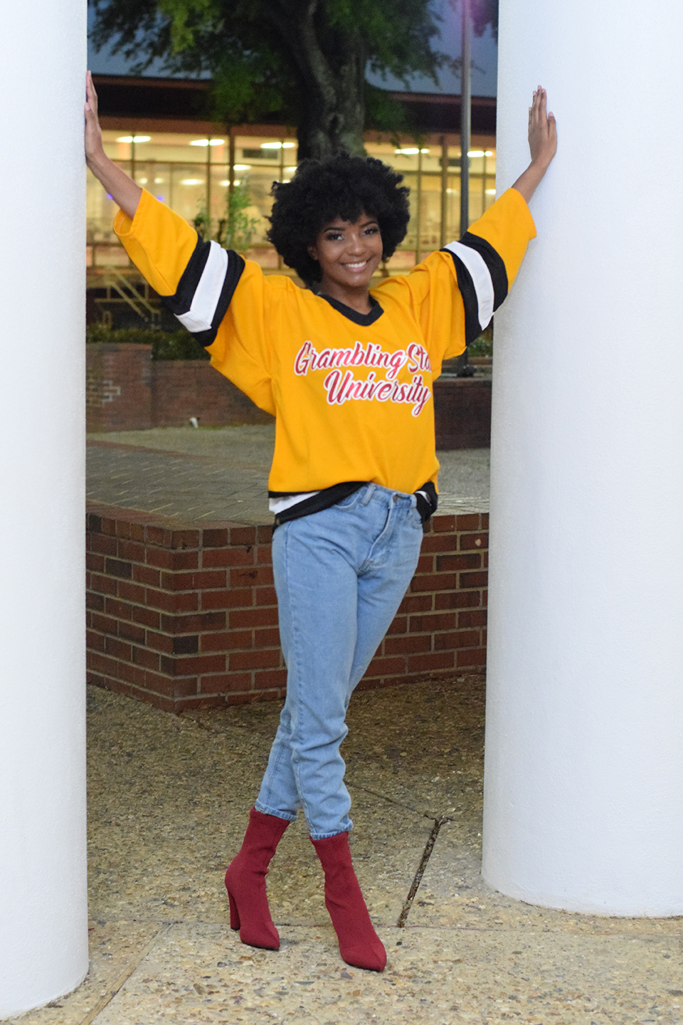 Black woman wearing university sweatshirt standing between two columns.