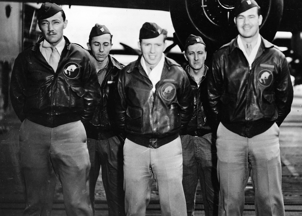 Five pilots standing in front of a plane for a group picture