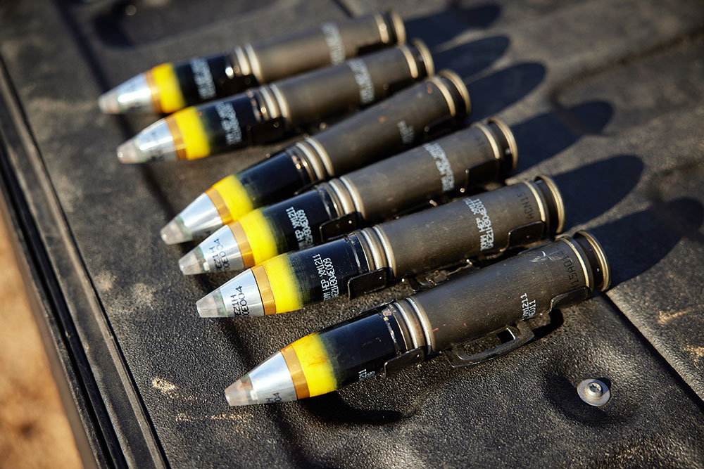 six rounds of medium caliber ammunition lined up on a case