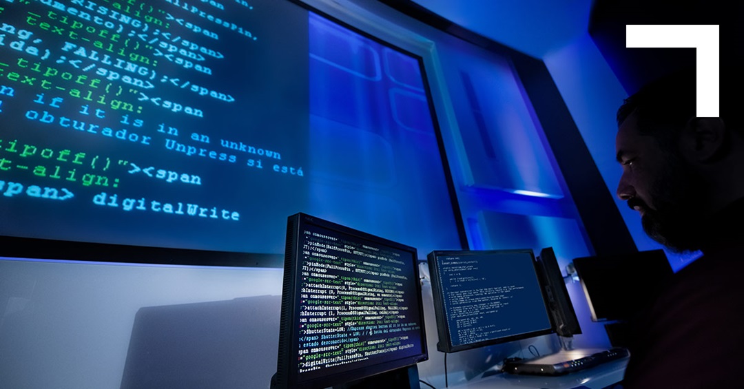 man looking at large computer screen with code