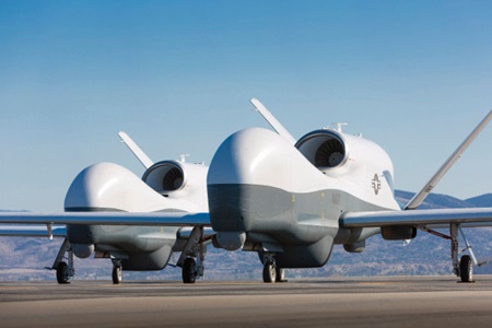 two military planes on tarmac with mountains and blue sky