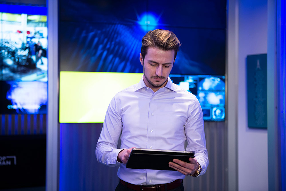 a man stands and looks down at a tablet