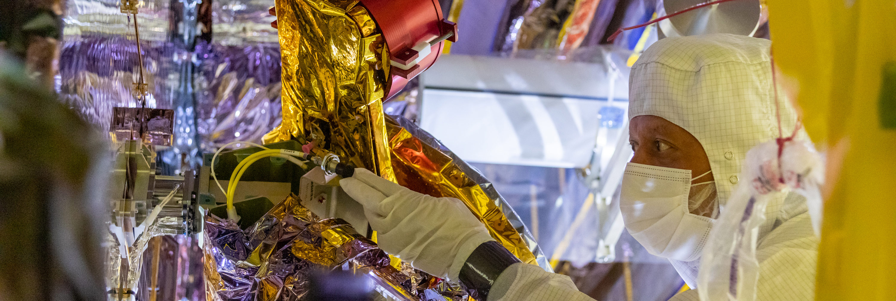 A man in a clean suit works on the James Webb Space Telescope