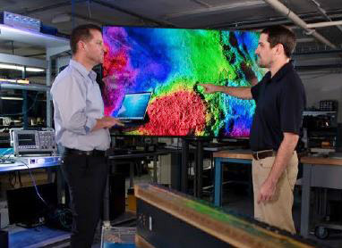 two males standing in front of a monitor