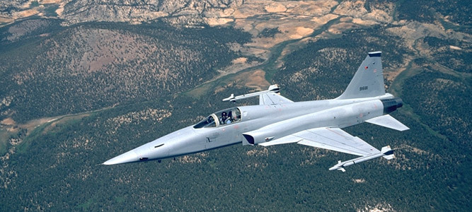 F-5 Tiger Fighter Jet flying over mountain range