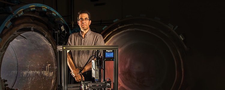 Man standing in front of a 3D printer in a manufacturing setting