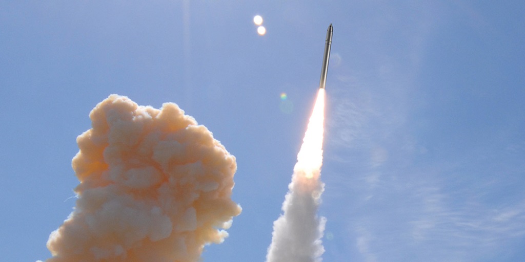 Missile being launched into the air with smoke coming up from the ground