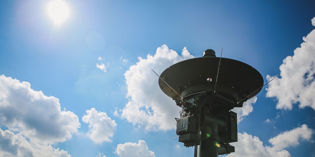 A weather satellite in front a bright blue sky.