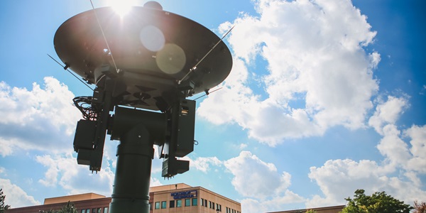 A weather satellite in front a bright blue sky.