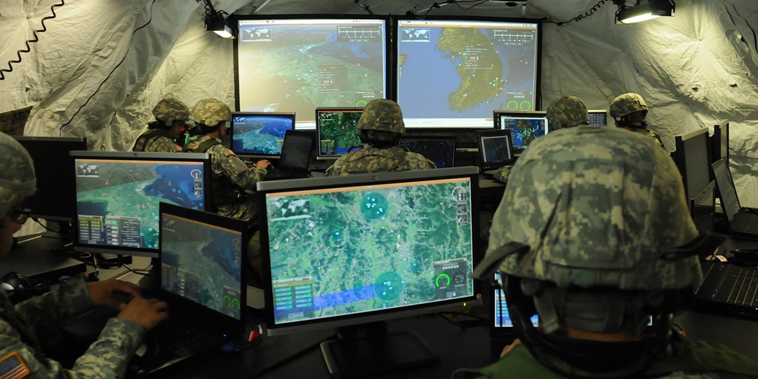 soldiers in tent looking at computer monitors