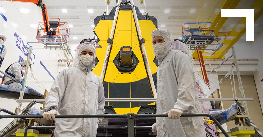 two engineer standing in front of the Webb telescope