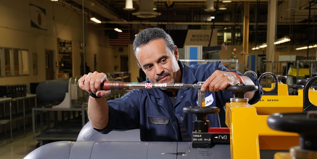 A man works with a litening pod on a factory floor