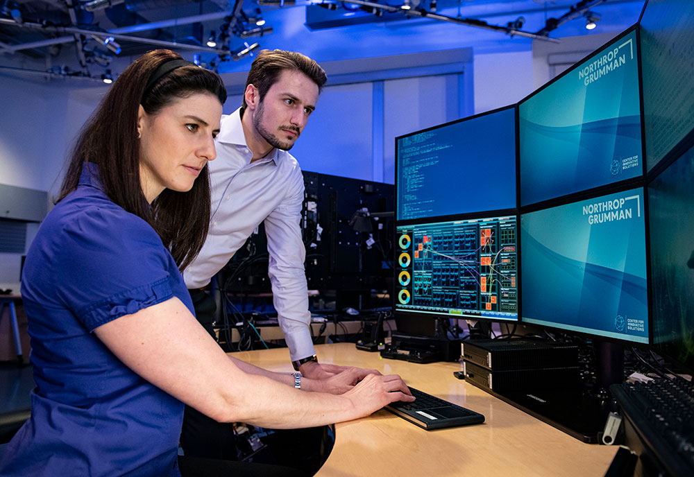 white male and female looking at computer monitors