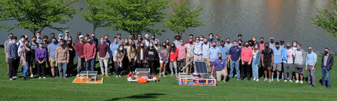 group of students standing in front of lake