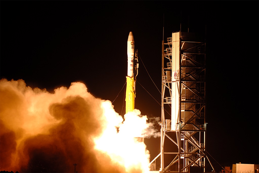 A rocket in front of a night sky launching from launch pad in to Space