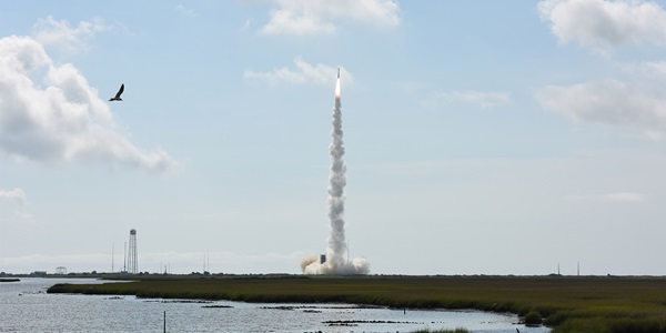 A rocket launching into space in front of a ocean