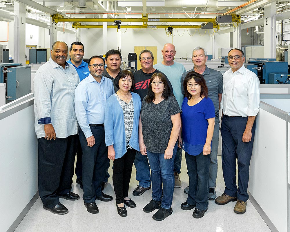 Eleven male and female team members pose in building